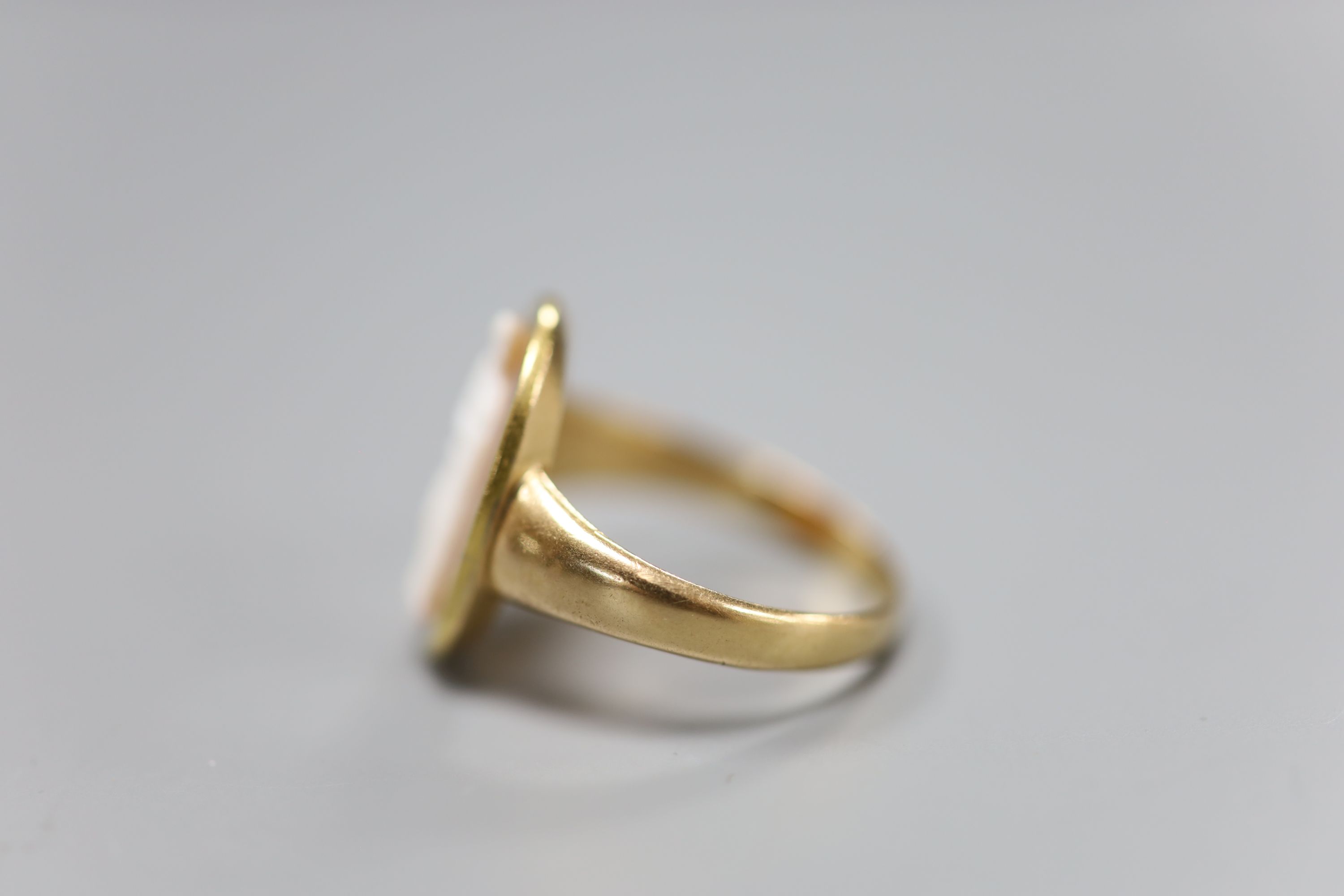 A 19th century yellow metal and oval cameo hardstone ring, carved with the figure of a lady with an urn, size R, gross 4.6 grams.